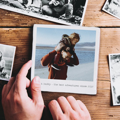 A personalised photo tile. The tile has the image of a father carrying a son on his shoulders printed on it, with sentimental words written beneath.