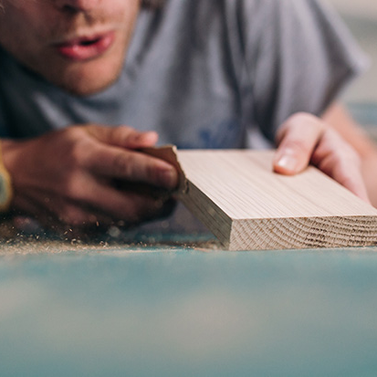 Close up of a man meticulously sanding down a solid oak block ready to be personalised.