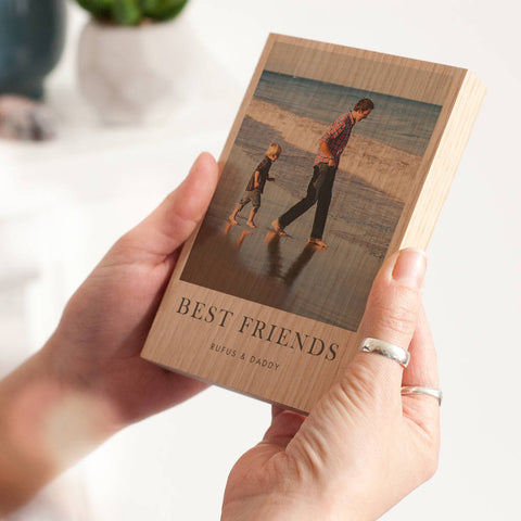 A personalised photo wood block. A photo has been printed on to a solid oak block of wood showing a father and son on a beach, with the words 'best friends' printed beneath.